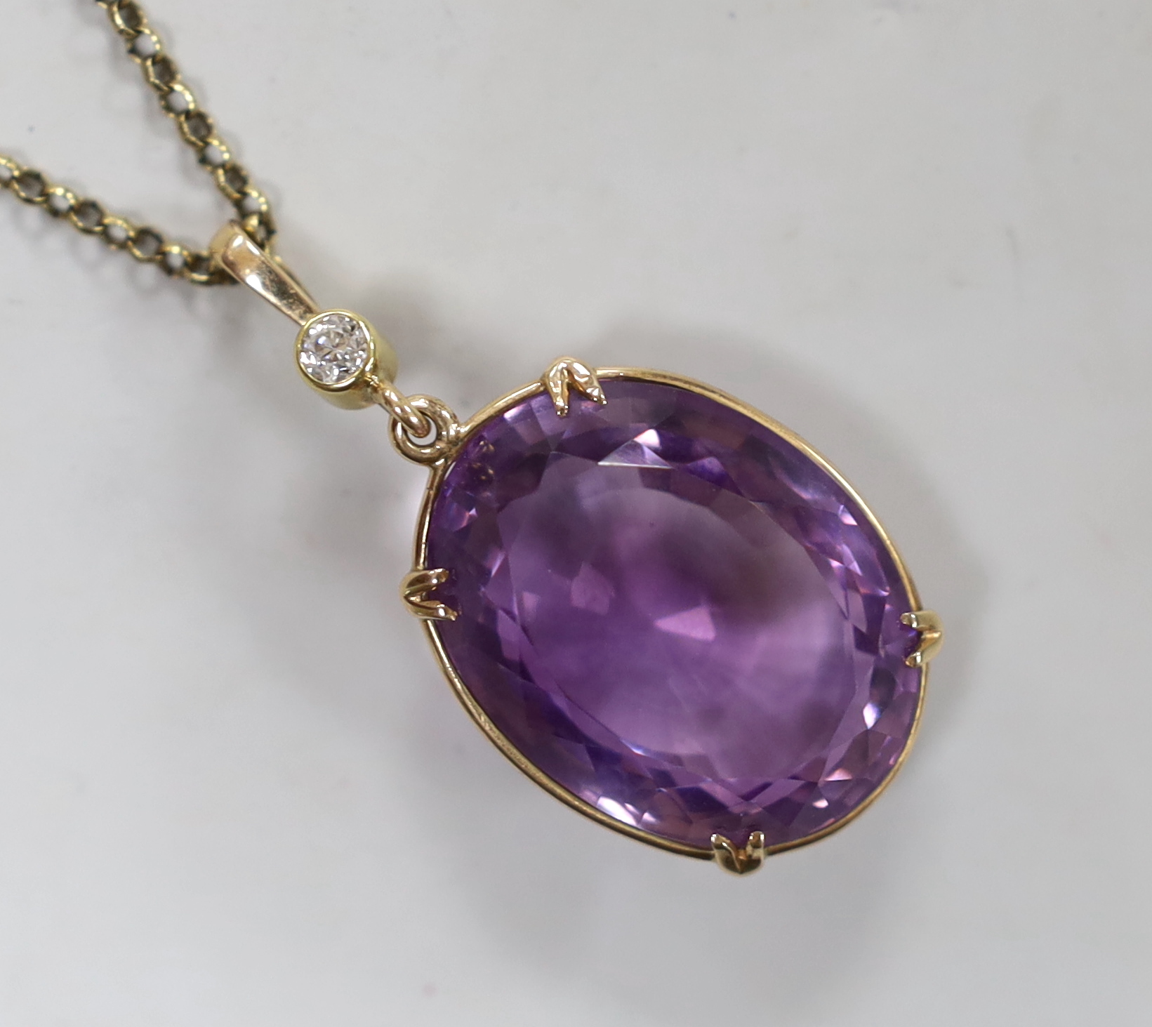 An early 20th century 15ct and single stone oval cut amethyst set pendant, with single stone diamond set bale, overall 42mm, on a gold plated chain.